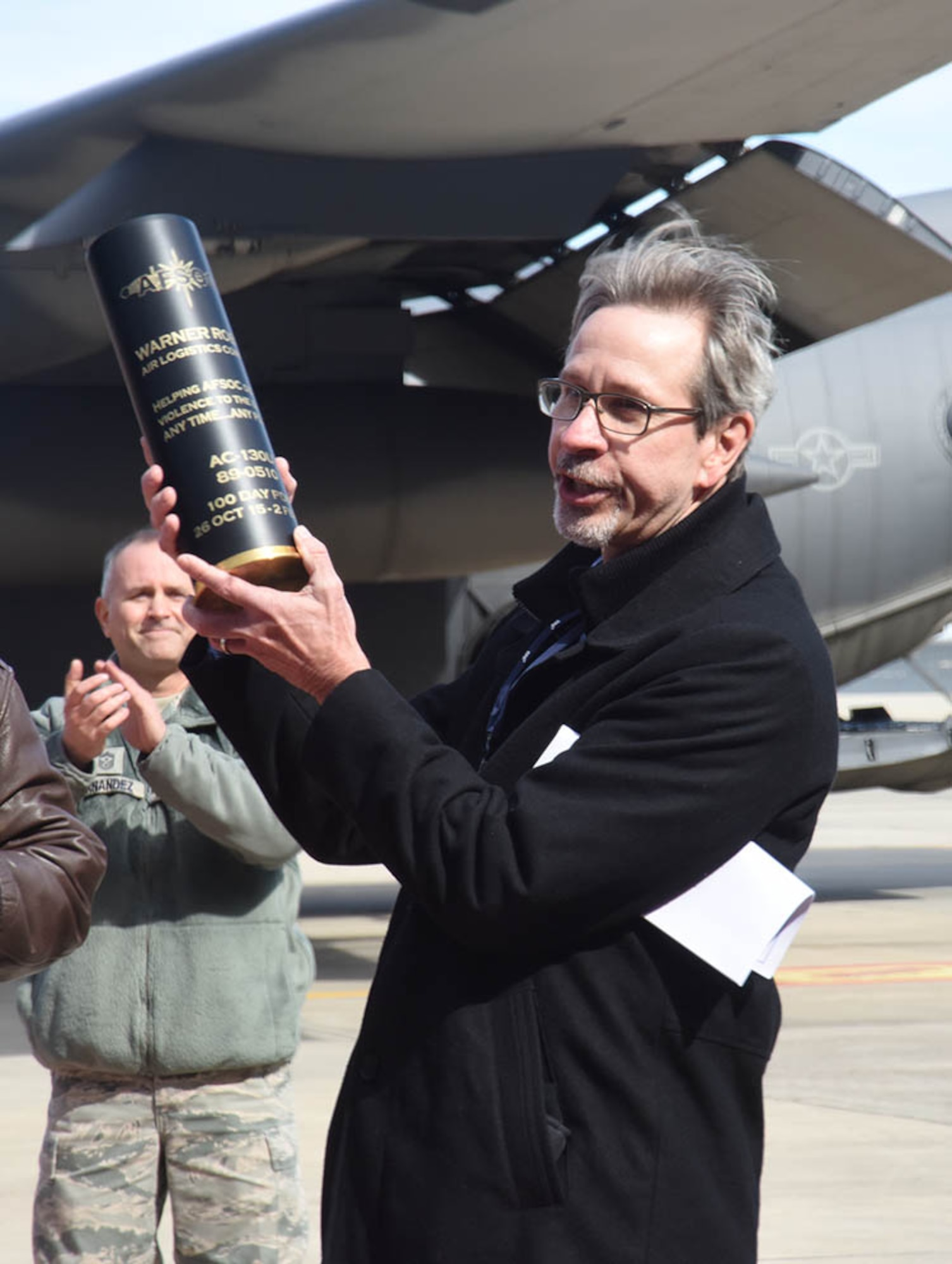 Doug Keene, WR-ALC  special assistant to the commander, holds up a 105mm round presented to the Warner Robins Air Logistics Complex from Maj. Gen. Haase on behalf of the 19,000 men and women who make up Air Force Special Operations Command. Haase was here to thank the workforce for the expedited work done on Special Ops aircraft over the course of the last year. (U.S. Air Force photo by Ed Aspera) 