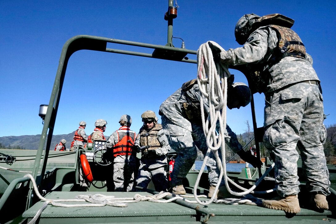 Crew members from the 132nd Multi-Role Bridge Company tie ropes and secure segments of an improved ribbon bridge on Whiskeytown Lake, near Redding, California February 11. The bridge is a critical tool for helping move vehicles and equipment when traditional bridges are unsafe or unavailable.