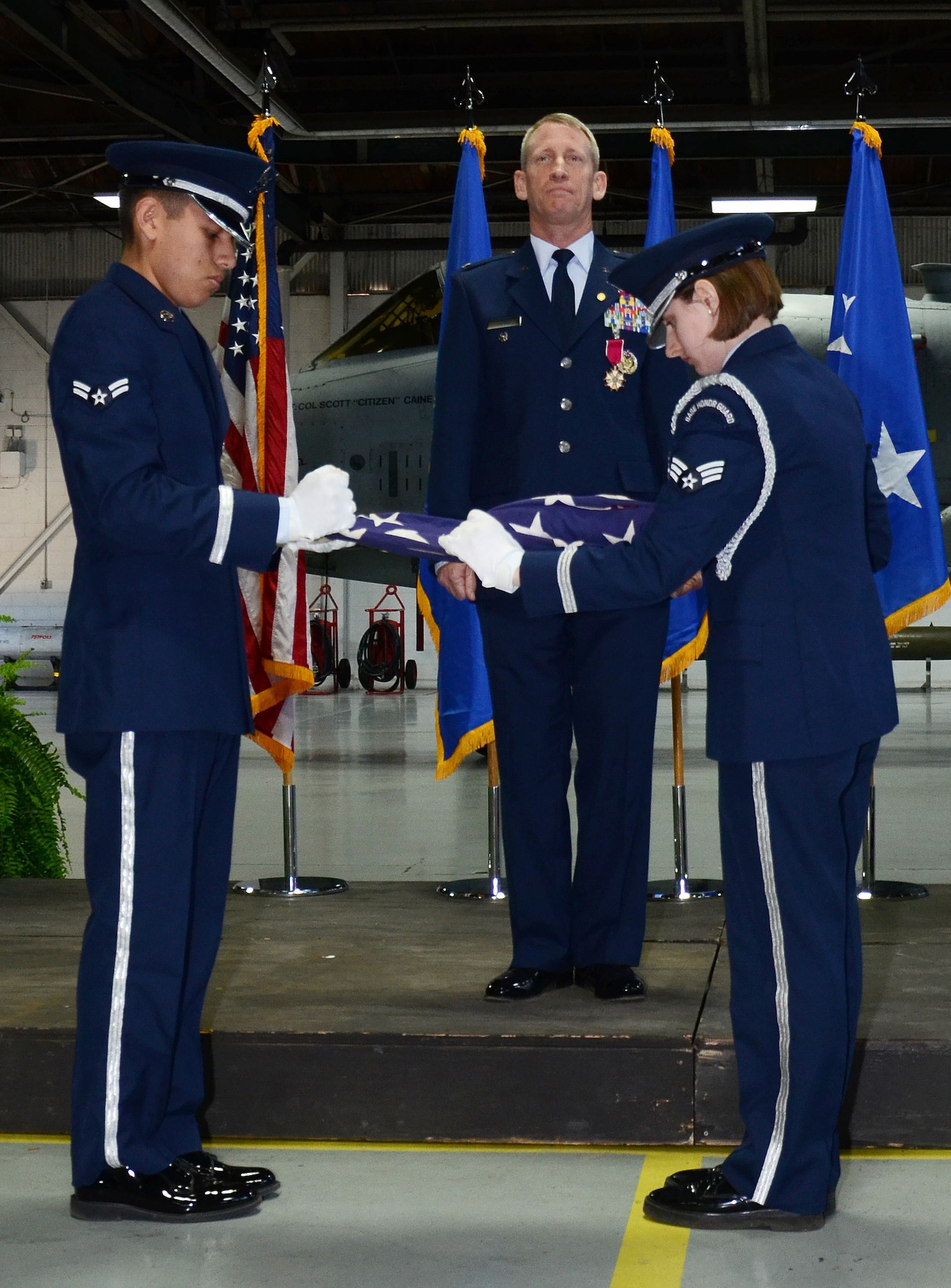 U.S. Air Force Col. Scott Caine (center), 9th Air Force vice commander, stands at attention Airman 1st Class Michael De La Cruz (left) and Senior Airman Caytlin Shreve (right), Shaw Air Force Base Honor Guard ceremonial guardsmen, fold the American Flag during Caine’s retirement ceremony, Shaw AFB, S.C., Feb. 10, 2017. As part of the ceremony, the American Flag was displayed and refolded to show respect and gratitude toward those who have fought and continue to fight for freedom. (U.S. Air Force photo by Tech. Sgt. Amanda Dick)