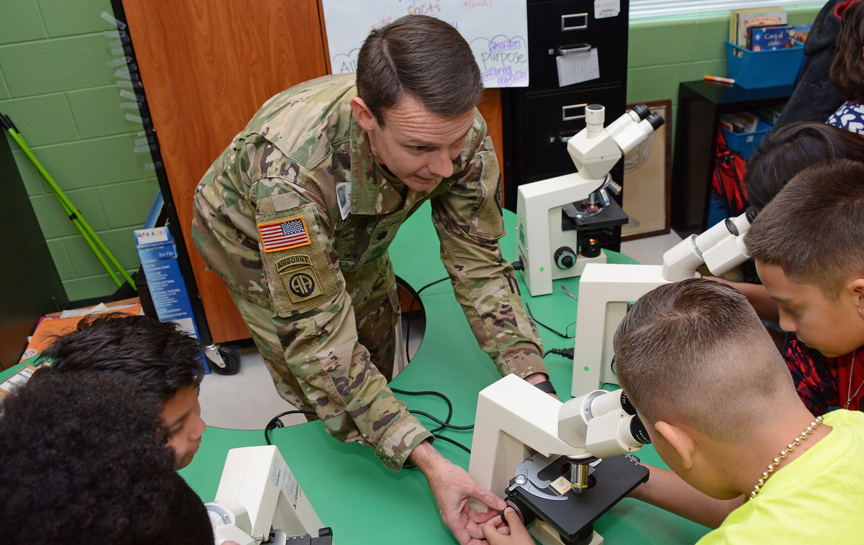 Lt. Col. Werner J. Barden, 264th Medical Battalion commander, assists East Terrell Hills Elementary School students viewing bacterial and pathogens under a medical microscope.
