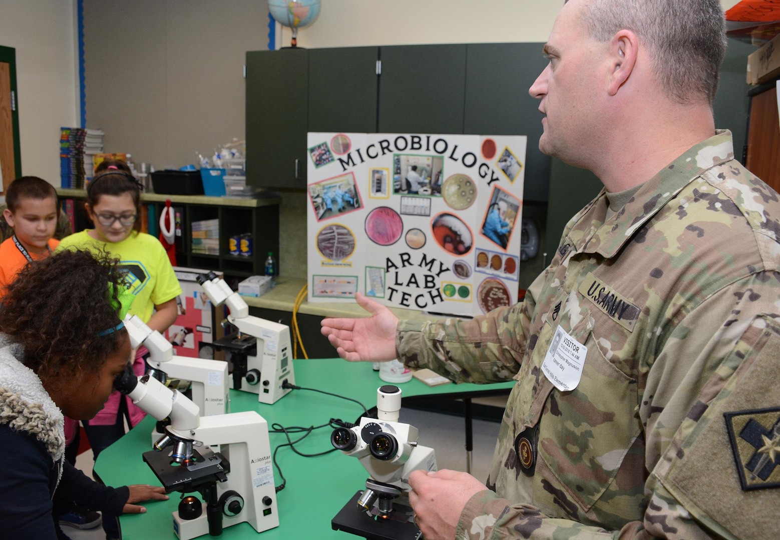Staff Sgt. Christopher Magnuson from the 264th Medical Battalion shows East Terrell Hills Elementary School students how to see bacteria and pathogens under a microscope during the school’s career day.