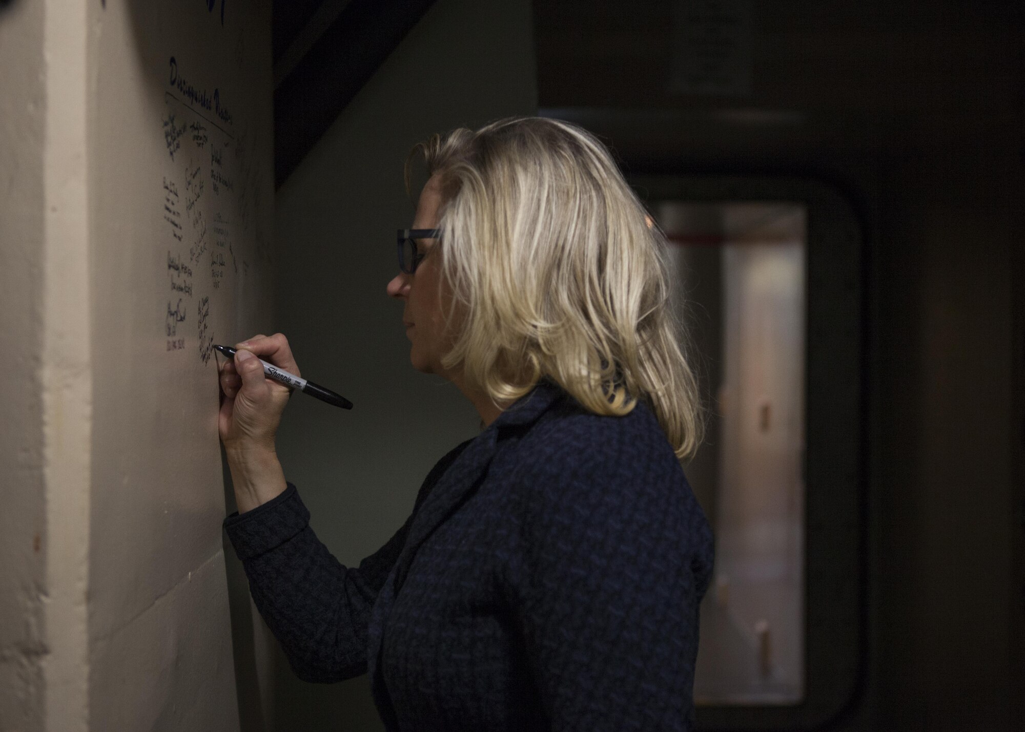 U.S. Rep. Liz Cheney signs a wall outside a launch control center in the F.E. Warren Air Force Base missile complex, Feb. 10, 2017. The wall displays the signatures of past distinguished visitors who have also visited that specific LCC. (U.S. Air Force photo by Lan Kim)
