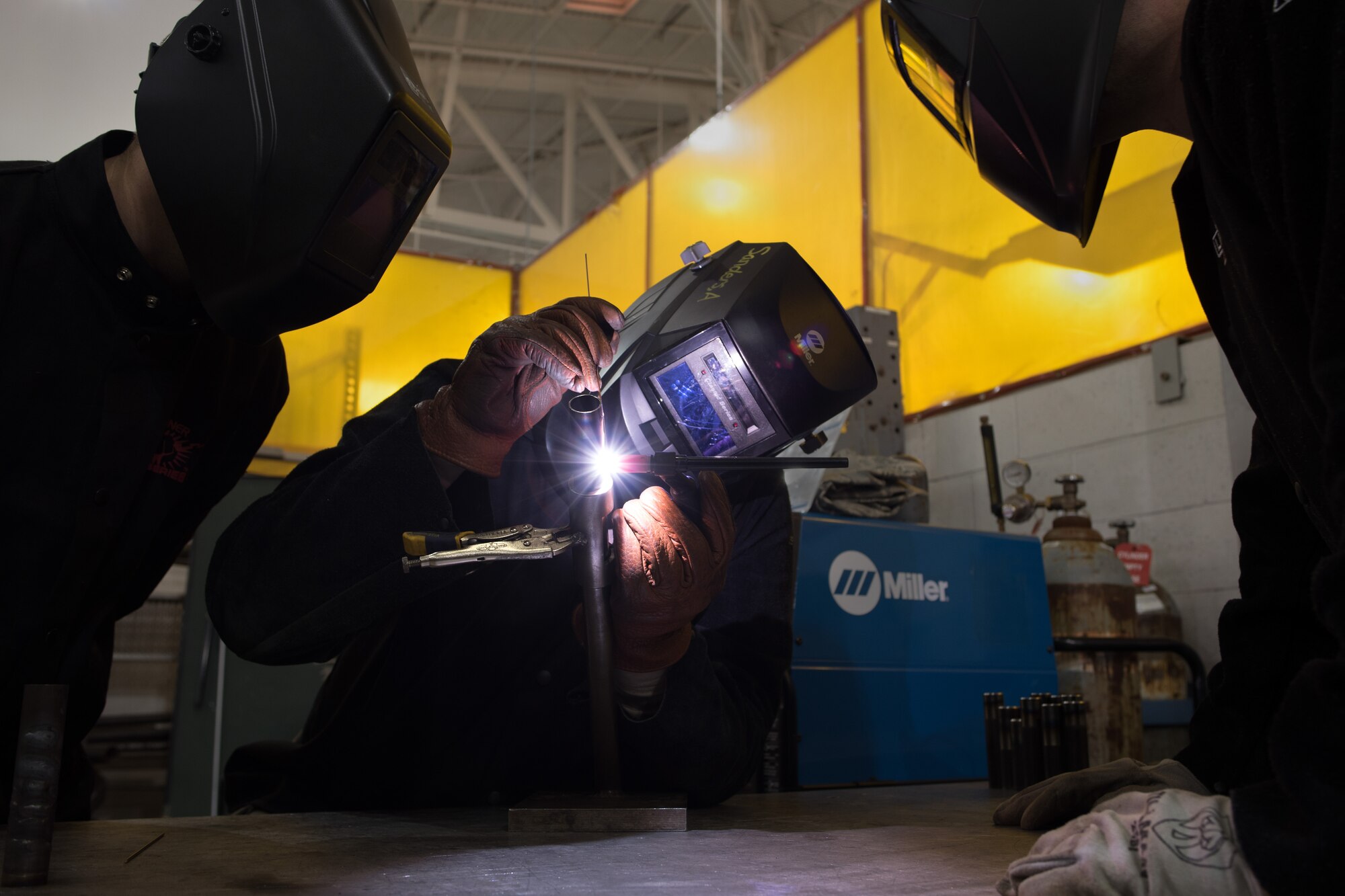 Senior Airman Aaron Sanders, 349th Maintenance Squadron aircraft metals technology specialist, practices tungsten inert gas welding at Travis Air Force Base, Calif., while Senior Airman Bryan Moffat, left, and Staff Sgt. Kyle Harshbarger, observe the detail of his work. Metals technology specialists must learn to precisely weld five different types of metals during their upgrade training.  The reservists are working alongside hundreds of their fellow Citizen Airmen from the 349th Maintenance Group to support Wrench Week 2017. The event offers them opportunities to accomplish ancillary training, upgrade training, and gain practical experience necessary to sharpen their primary job skills. (U.S. Air Force photo by Ken Wright)