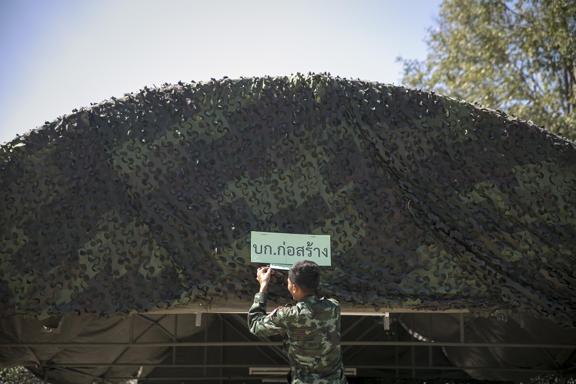A soldier with the Royal Thai Army hangs a construction sign on a tent at Ban Non Lueam School in Korat Province, Thailand, Jan. 27, 2017 in support of COBRA GOLD 17 (CG17). CG17 emphasizes coordination on civic action, such as humanitarian assistance and disaster relief, seeking to expand regional cooperation and collaboration in vital areas of the Indo-Asia-Pacific region. (U.S. Marine Corps photo by Sgt. Ally Beiswanger)