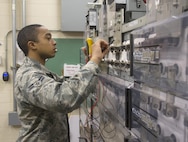 Airman 1st Class Nicklaus Norman, 88th Communications Squadron Telephone Repair Shop voice network system technician, checks the voltage produced by a battery in his shop’s direct-current power plant, Jan. 27, 2017 at Wright-Patterson Air Force Base, Ohio. The base’s phone system has redundant backup power supplies, including emergency generators and batteries. (U.S. Air Force photo by R.J. Oriez/Released)