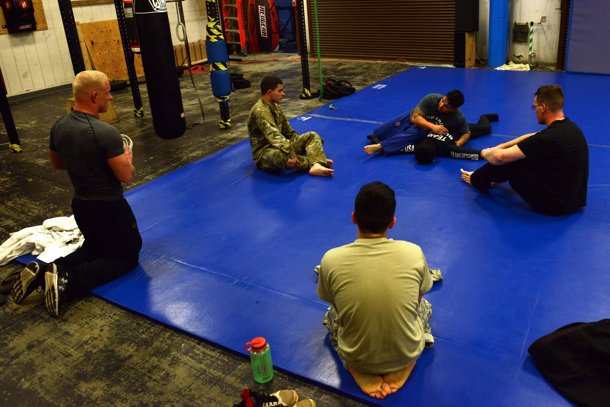 Combatives House students and an instructor sit in a circle as Staff Sgt. Joel Lung, U.S. Army Central battalion intelligence noncommissioned officer in charge, demonstrates a grappling technique on a dummy at Shaw Air Force Base, S.C., Feb. 7, 2017. The Combatives House offers Levels I and II combatives classes, and also holds practices for competitions. (U.S. Air Force photo by Airman 1st Class Destinee Sweeney)