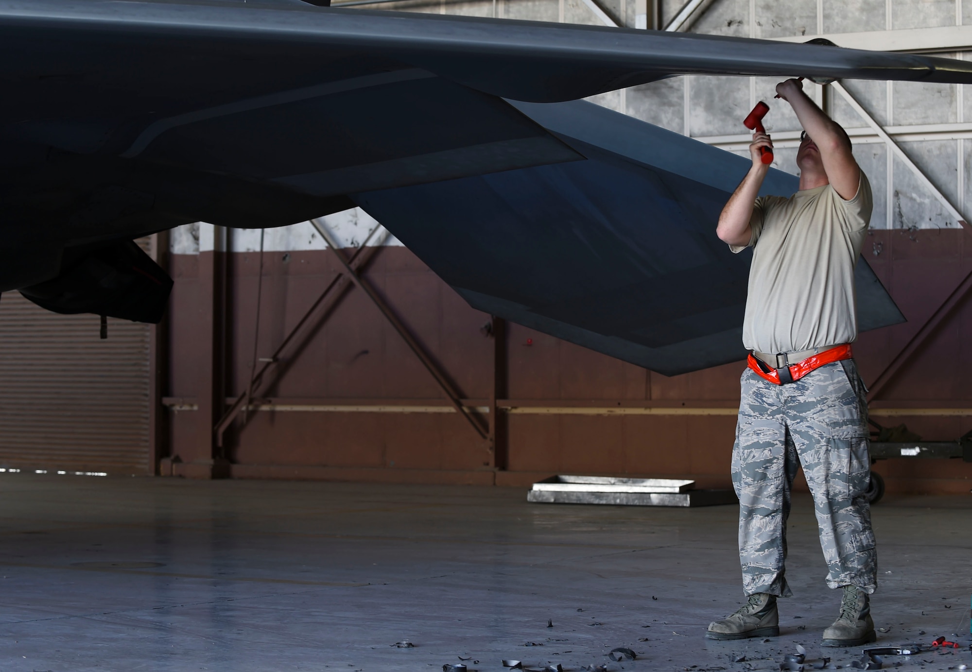 U.S. Air Force Staff Sgt. Zachary Dunn, 192nd Fighter Wing low observable aircraft structures technician, hammers radar absorbent material from an F-22 Raptor during Red Flag 17-1 at Nellis Air Force Base, Nev., Feb. 3, 2017. The material was covering a light panel that will later be fixed by  27th Aircraft Maintenance Unit maintainers. (U.S. Air Force photo by Staff Sgt. Natasha Stannard)