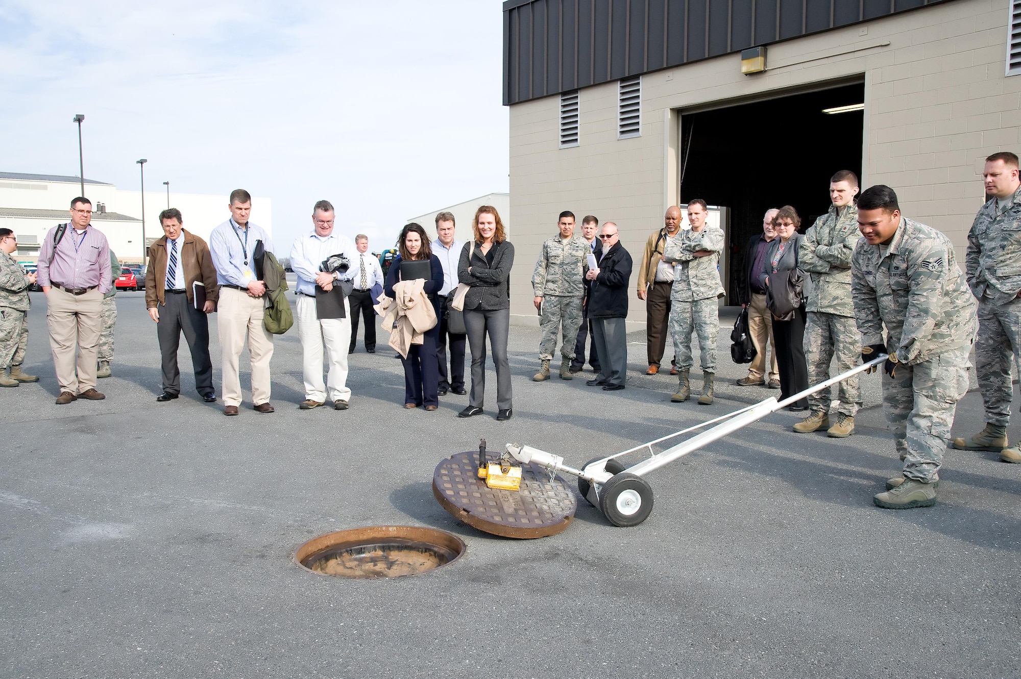 Senior Airman Octavious Tookes, 436th Aerial Port Squadron fleet service specialist, uses a magnetic lift to remove a sewer cover Feb. 8, 2017, at Dover Air Force Base, Del. Tookes showed members of Air Mobility Command’s “Aerial Port of the Future” study team from Scott Air Force Base, Ill., how the lift is used to remove the cover prior to an aircraft lavatory service truck emptying its holding tank back in the APS compound. (U.S. Air Force photo by Roland Balik)