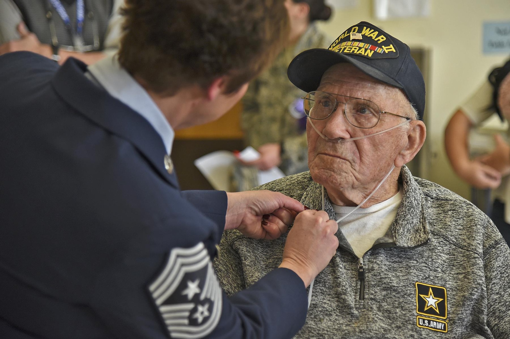 Chief Master Sgt. Shannon Rix, 92nd Air Refueling Wing command chief, gives a commemorative National Salute to Veteran Patients Week pin to Mike Olmstead Feb. 13, at Mann-Grandstaff VA Medical Center, Washington. Olmstead served in the Army from 1944 to 1947 during World War II and is currently the community living center’s oldest resident. (U.S. Air Force photo/Senior Airman Mackenzie Richardson)
