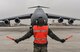 Senior Airman Earl Shelton, 721st Aircraft Maintenance Squadron aerospace maintenance technician, marshals a C-5M Super Galaxy into place at Ramstein Air Base, Germany, Jan. 24, 2017. After it was in place, 721st AMXS Airmen chocked the wheels, plugged it into a generator, checked tire pressure, refilled oil, and refueled the aircraft. On average, the 721st AMXS inspects, services, and repairs 30 aircraft in a single day, as part of the 521st Air Mobility Operations Wing at Ramstein.  (U.S. Air Force photo by Senior Airman Tryphena Mayhugh)