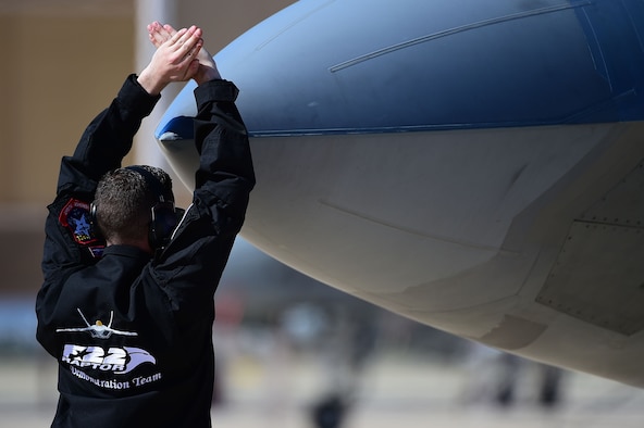 U.S. Air Force Senior Airman Alexander Niccum, F-22 Raptor Demonstration Team crew chief, signals for the F-22 Raptor pilot to stop during the 2017 Heritage Flight Training and Certification Course at Davis-Monthan Air Force Base, Ariz., Feb. 10, 2017. The Demonstration Team uses a non-verbal communication process to assist the pilot with take-off and landings. (U.S. Air Force photo by Senior Airman Kimberly Nagle)