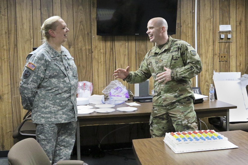Army Maj. Chris Matthews from the 318th Press Camp Headquarters gives Army Sgt. 1st. Class Deborah Hartman a cake and cards signed by the Soldiers of the 318th Press Camp Headquarters with anecdotes and well wishes during her last weekend as the unit administrator, Forest Park, Ill., February 11, 2017. (U.S Army photo by Sgt. Alfonso Corral)