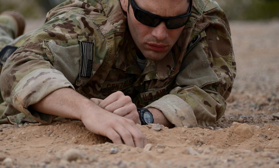 Senior Airman Moises Gonzalez, 56th Civil Engineer Squadron explosive ordnance disposal team member removes dirt covering a roadside bomb during the improvised explosive device sweep training Feb. 6, 2017, at the Barry M. Goldwater Air Force Range in Gila Bend, Az. Once the IED threat is identified, EOD Airmen carefully expose the device in order to defuse it. (U.S. Air Force photo by Airman 1st Class Alexander Cook)  