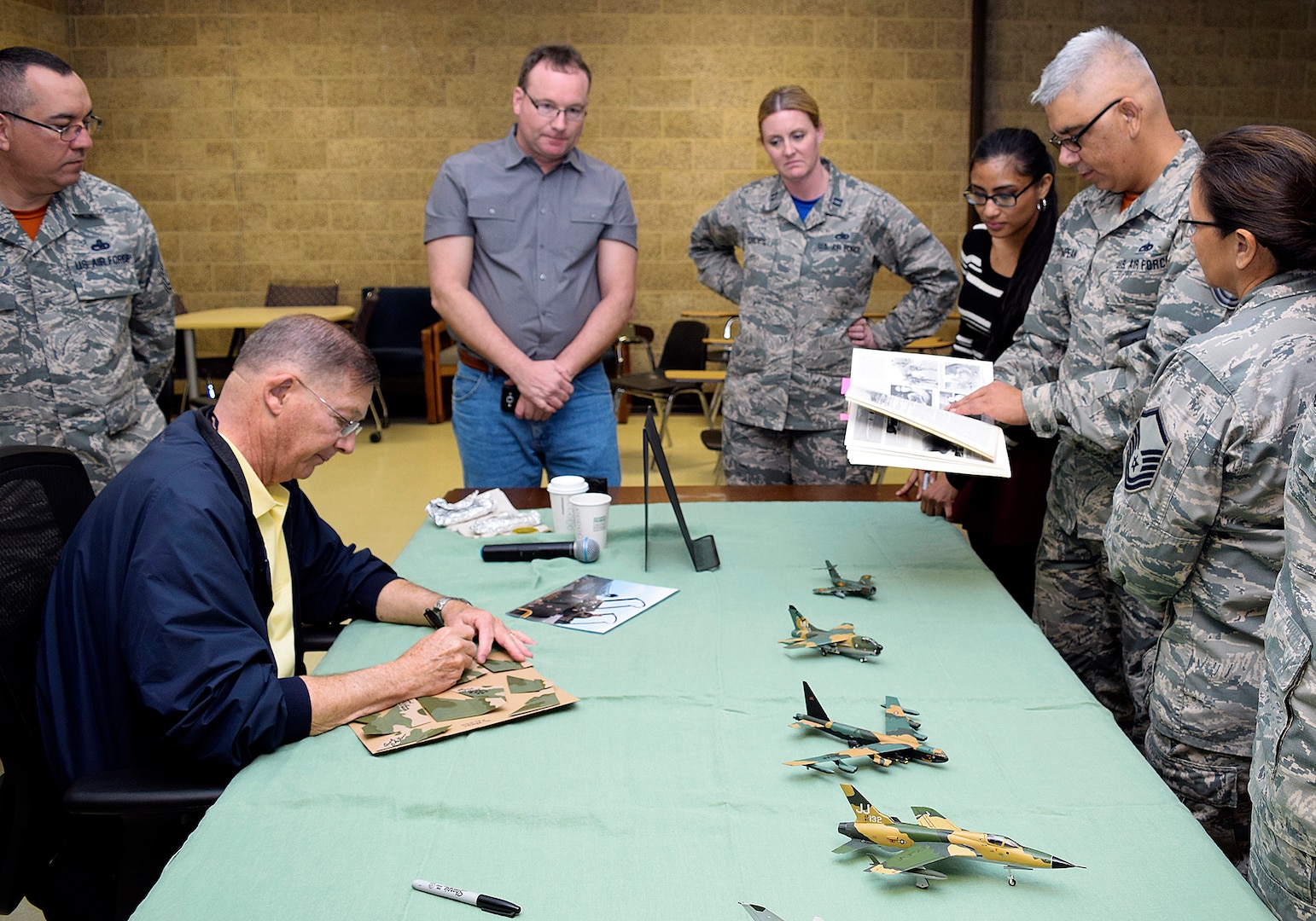 Retired Air Force ACE Col. Chuck Debellevue, the highest-scoring Ace of the Vietnam War, signs memorabilia after speaking to members of the 433rd Maintenance Group Feb. 10, 2017 at Joint Base San Antonio-Lackland, Texas. Debellevue served as the guest speaker during the 433rd Airlift Wing awards banquet.  (U.S.  Air Force photo by Maj. Timothy Wade)