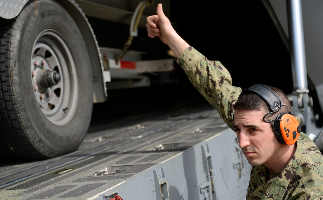 U.S. Coast Guard Machinery Technician 1st Class Eric Zupan, Port Security Unit 305 crewmember, signals a to forklift operator while loading security boats onto a C-17 Globemaster III at Joint Base Langley-Eustis, Va., Feb. 8, 2017. Zupan and his team loaded their equipment onto the aircraft in preparation for a joint task force deployment. (U.S. Air Force photo by U.S. Airman 1st Class Kaylee Dubois)