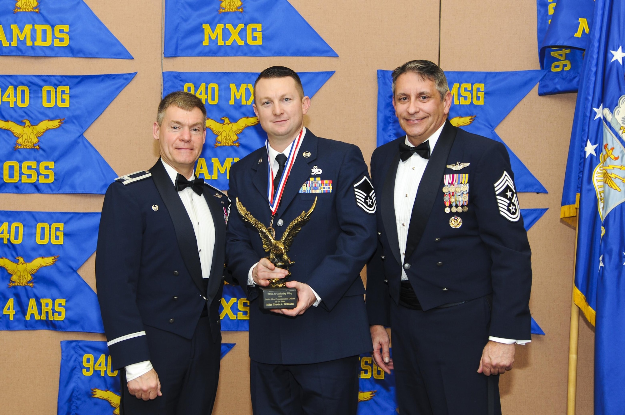 Master Sgt. Travis Williams, 940th Maintenance Squadron inspection dock chief, accepts the Senior NCO of the Year award, presented by Col. Craig C. Peters, 940th Air Refueling Wing commander, and Chief Master Sgt. Carmen Madia, 940 ARW command chief Feb. 11, 2017 at Beale Air Force Base, California. Wing members and guests gathered to honor the hard work of the nominees and winners at the Outstanding Airmen of the Year banquet. (U.S. Air Force by Senior Airman Tara R. Abrahams)