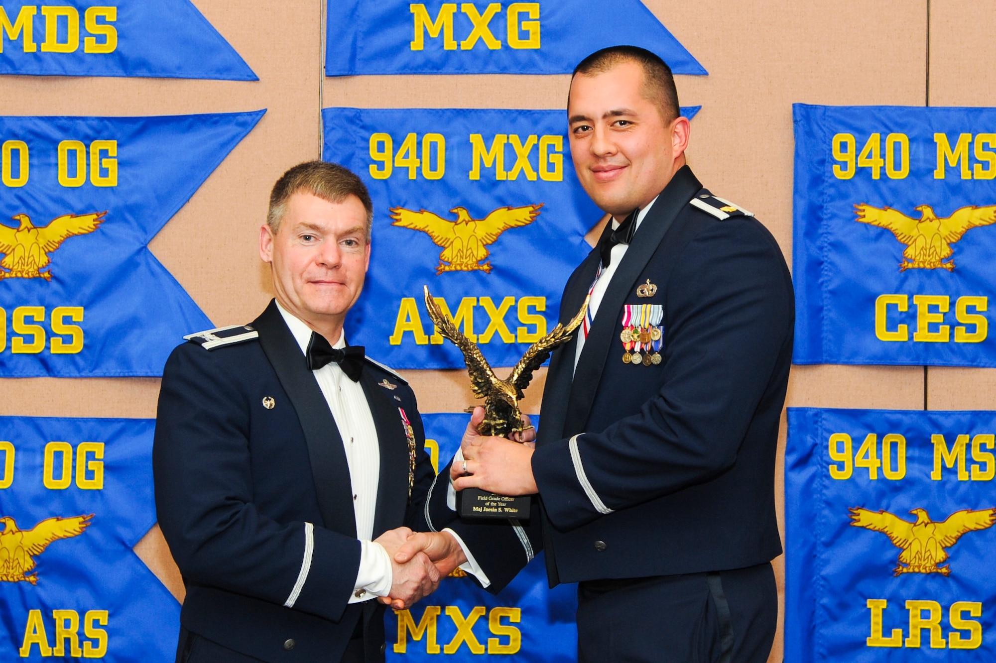 Maj. Jaesin White, 940th Logistics Squadron commander, accepts the Field Grade Officer of the Year award, presented by Col. Craig C. Peters, 940th Air Refueling Wing commander. Airmen around the wing were named Outstanding Airmen of the Year at the wing’s OAY banquet. (U.S. Air Force by Senior Airman Tara R. Abrahams)