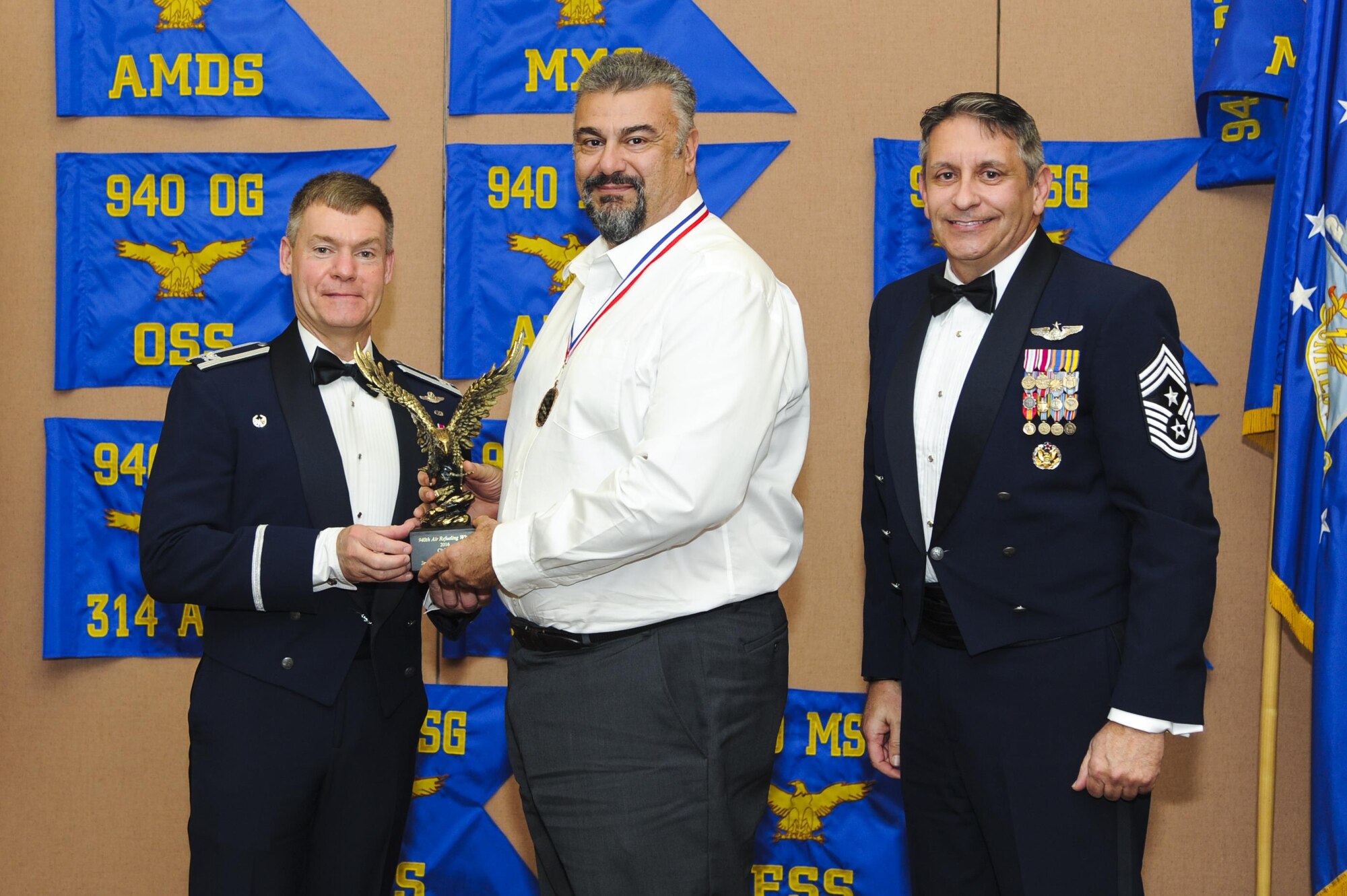 Joe Marturano, 940th Logistics Readiness Squadron transportation specialist, accepts the Civilian of the Year award, presented by Col. Craig C. Peters, 940th Air Refueling Wing commander, and Chief Master Sgt. Carmen Madia, 940 ARW command chief. Five Airmen from around the wing were named Outstanding Airmen of the Year at the OAY banquet. (U.S. Air Force by Senior Airman Tara R. Abrahams)
