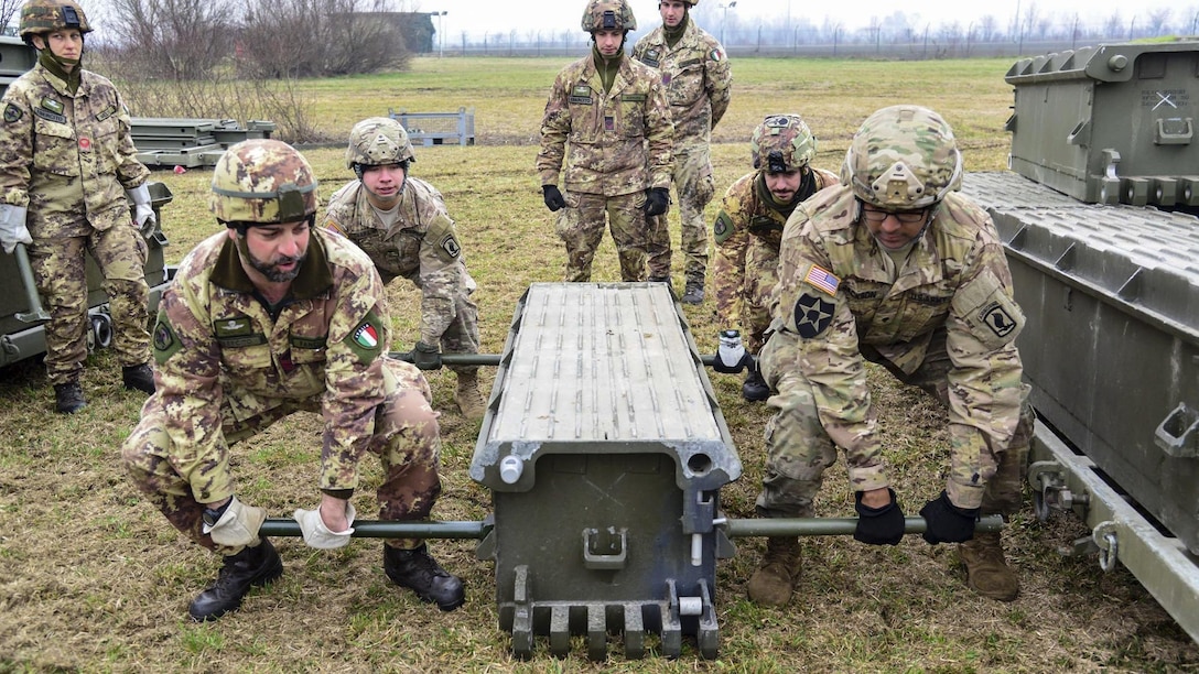 U.S. and Italian soldiers assemble a girder bridge near Rovigo, Italy, Feb. 13, 2017. The bridge provides a wide roadway that a crew can assemble with minimal support. The U.S. soldiers are paratroopers assigned to the 173rd Airborne Brigade, 54th Brigade Engineer Battalion. Photo by Graigg Faggionato