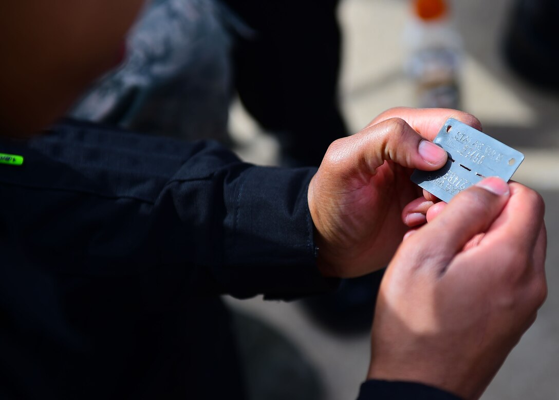 U.S. Air Force Tech. Sgt. Darshele Green, F-22 Raptor Demonstration Team avionics specialist, reads the Prisoner of War tags of Walter Ram, a former POW, during the 2017 Heritage Flight Training and Certification Course at Davis-Monthan Air Force Base, Ariz., Feb. 11, 2017. Ram met with several members of the F-22 Demonstration Team and told his story, including his time as a prisoner. (U.S. Air Force photo by Senior Airman Kimberly Nagle)