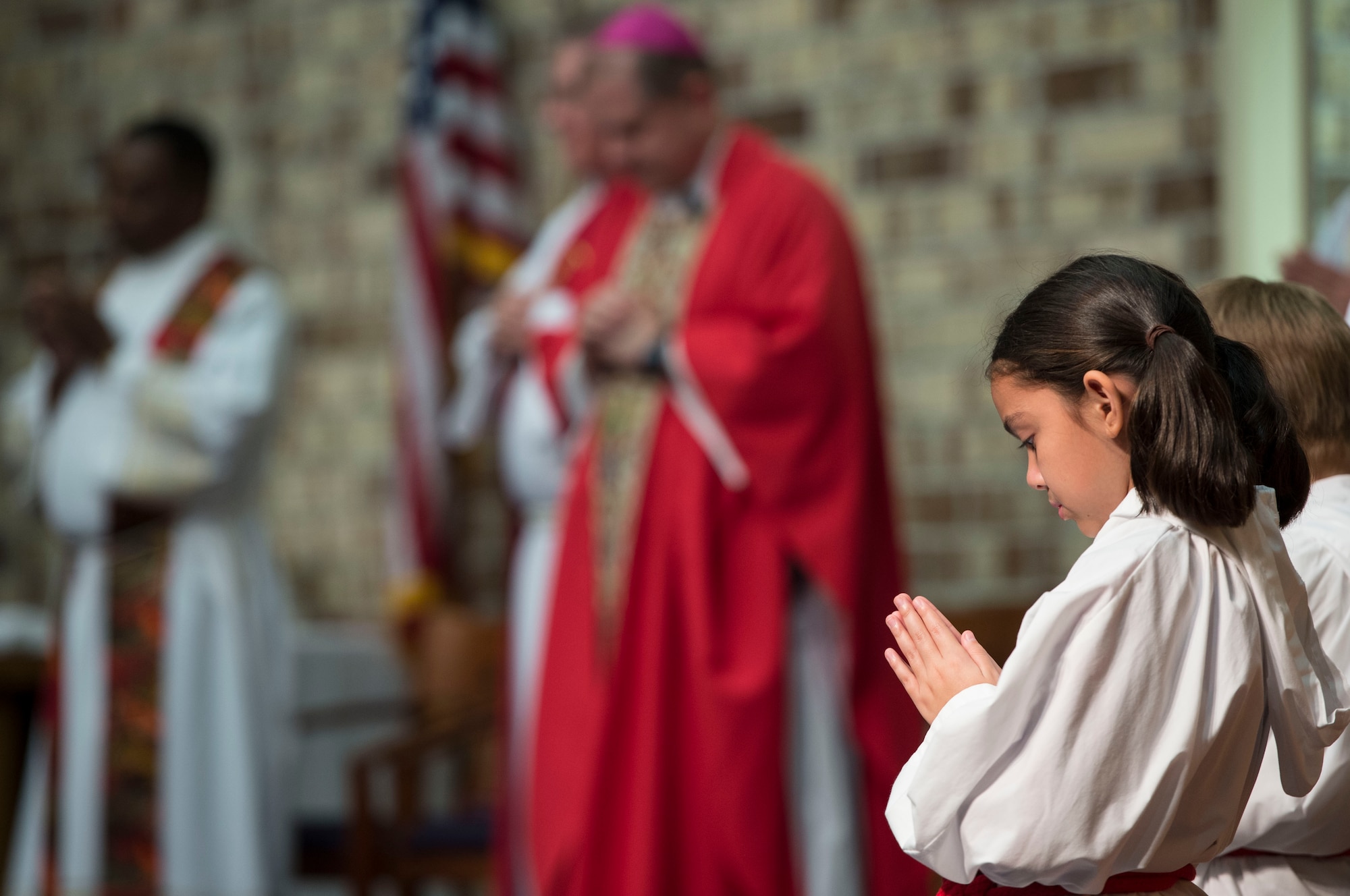 An altar girl prays during Confirmation Mass, Feb. 14, 2017, at Moody Air Force Base, Ga. Pope John Paul II created the Archdiocese for the Military Services in 1985 to provide the Catholic Church's full range of pastoral ministries and spiritual services to those in the United States Armed Forces. The Archbishop for the Military Services is responsible for the spiritual welfare of more than 1.8 million men, women and children. (U.S. Air Force photo by Andrea Jenkins/Released)