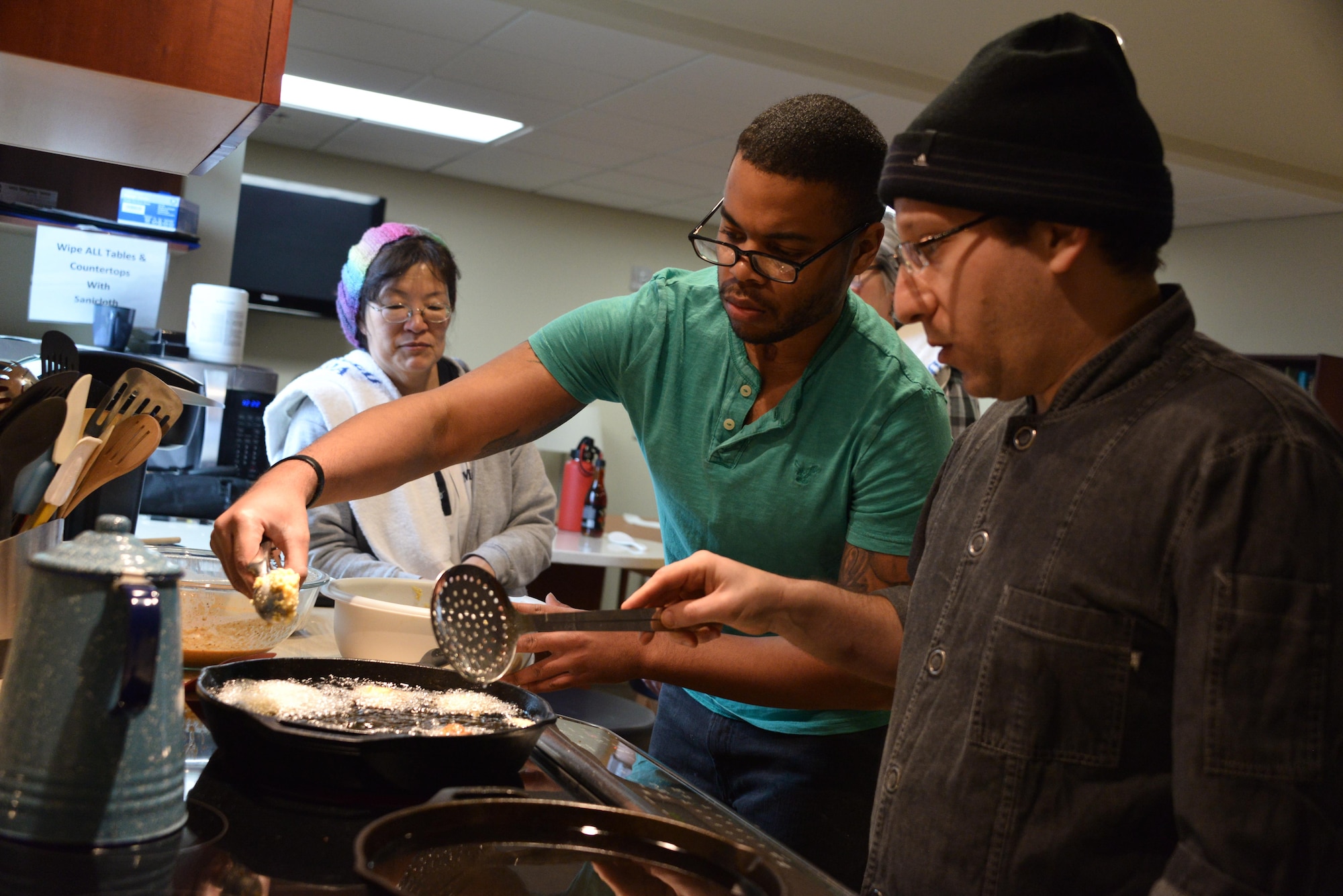 Staff Sgt. Rasheed, 7th Intelligence Squadron, lays a piece of fish in a fryer while Chef Egg observes during cooking class as part of his occupational therapy sessions January 17, 2017 at Walter Reed Military Medical Center Bethesda, Md. Rasheed suffered a cerebral aneurysm in early 2016, part of his recovery to return to service is working on occupational exercises to get him rehabilitated. (U.S. Air Force photo/Staff Sgt. Alexandre Montes)