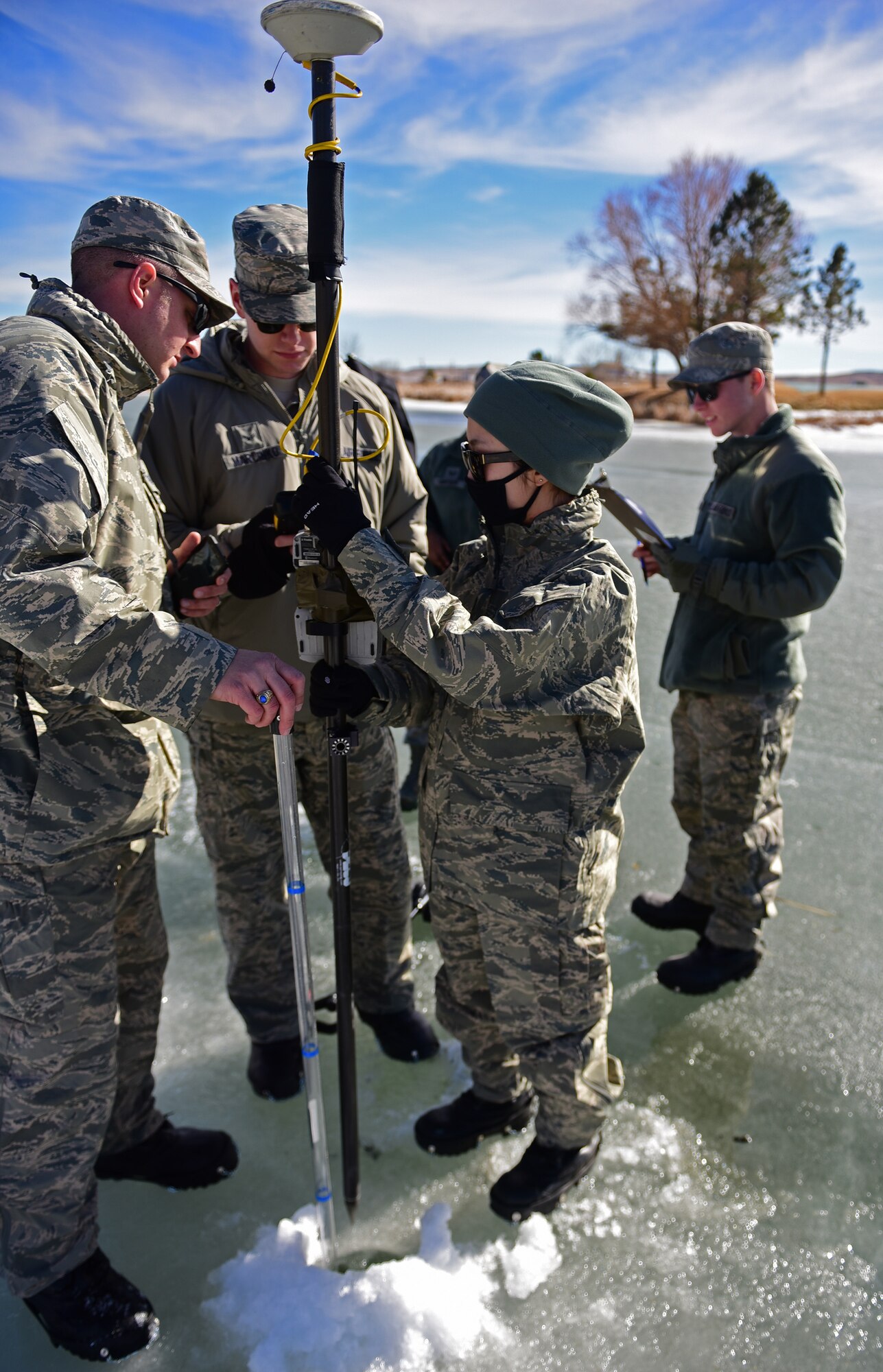 Airman 1st Class Clara Song, an engineering technician assigned to the 28th Civil Engineer Squadron, keeps survey equipment steady as other 28th CES Airmen record the water level readings at Ellsworth Air Force Base, S.D., Feb. 14, 2017.  The readings taken from the lake will help determine the need for future projects. (U.S. Air Force photo by Senior Airman James L. Miller)