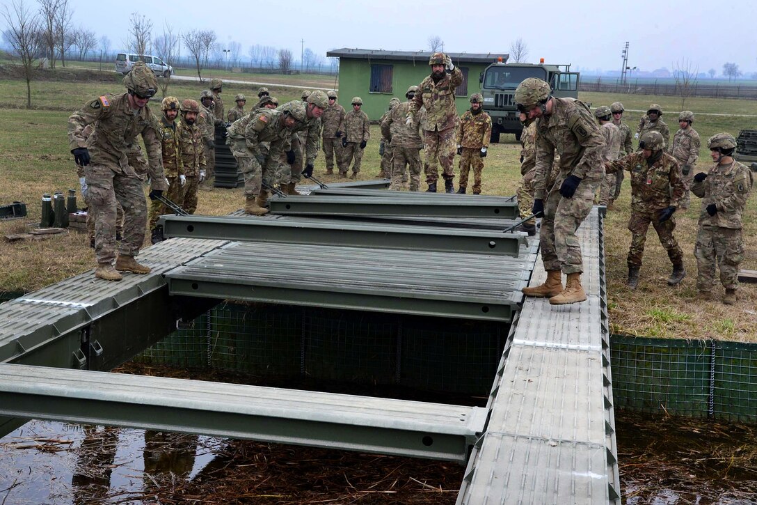 U.S. and Italian soldiers set steel planks while assembling a girder bridge near Rovigo, Italy, Feb. 13, 2017. Army photo by Graigg Faggionato
