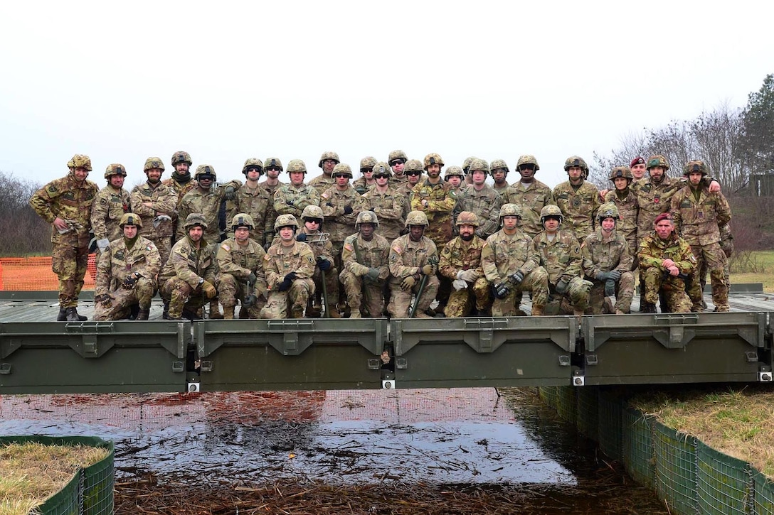 U.S. and Italian soldiers pose for a photograph after assembling the girder bridge they are standing on near Rovigo, Italy, Feb. 13, 2017. The U.S. soldiers are paratroopers assigned to the 173rd Airborne Brigade, 54th Brigade Engineer Battalion. Army photo by Graigg Faggionato