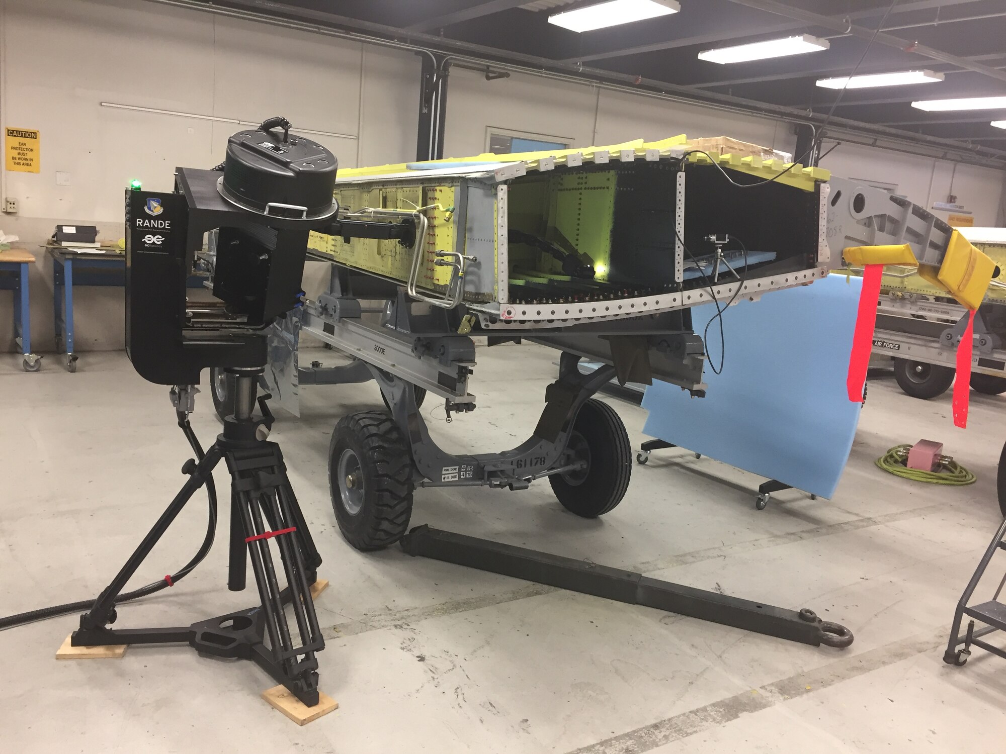 The Remote Access Nondestructive Evaluation robotic snake arm inspeciton tool is easily portable and can be quickly set up for use.  Here, it is shown inserted to aircraft wing through small access port during a recent demonstration at Hill Air Force Base. (U.S. Air Force photo/Charles Buynak)