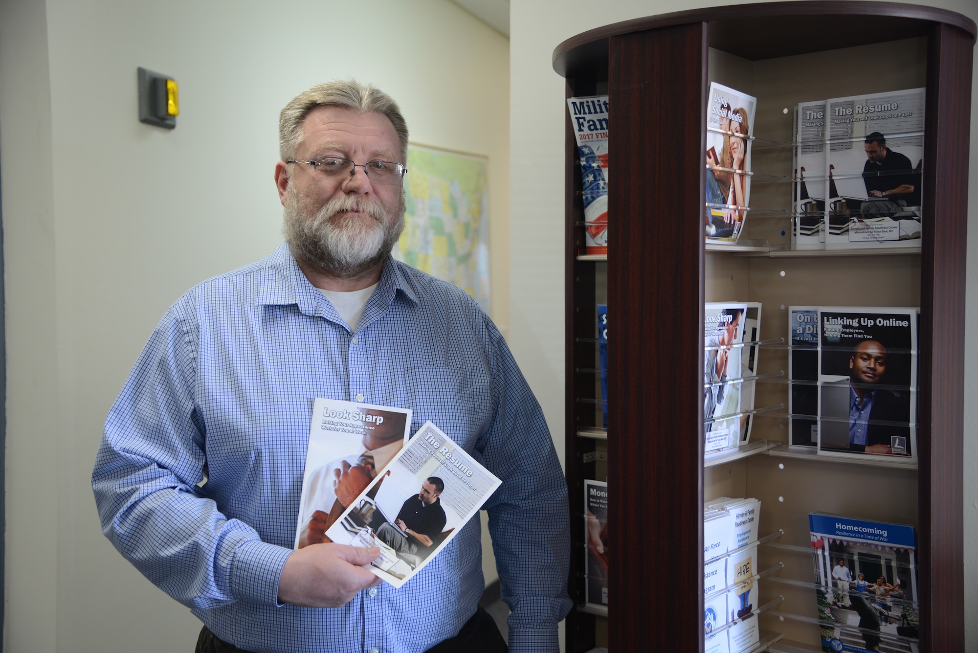 Dave Burger, 341st Force Support Squadron Airman and Family Readiness Center transition program manager, holds up resume and job interview informational pamphlets, Feb. 14, 2017, at Malmstrom Air Force Base, Mont. Burger understands the career challenges military spouses can face and wants to share the programs and opportunities the A&FRC has to offer. (U.S. Air Force photo/ Staff Sgt. Delia Marchick)