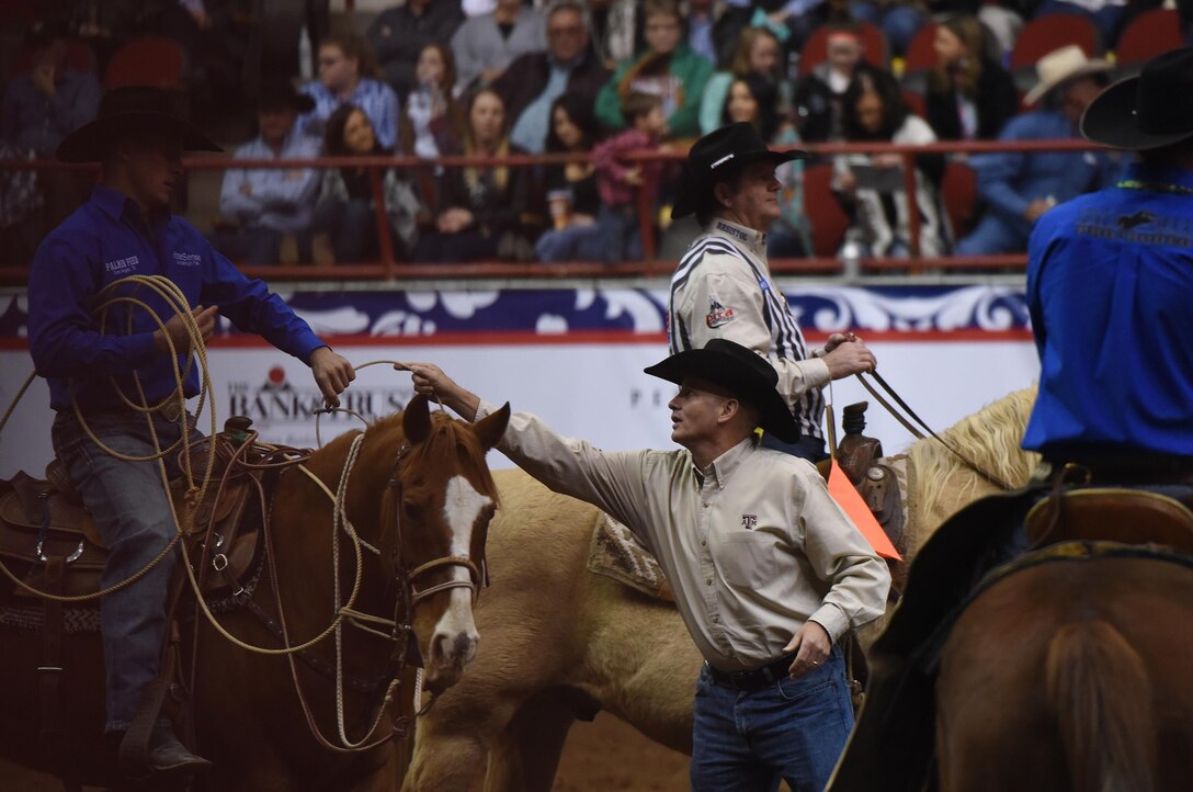 U.S. Air Force Col. Michael Downs, 17th Training Wing Commander, hands a tie-down rope, or piggin' string, back to Cody Waldrop, San Angelo Stock Show and Rodeo competitor, during the 85th Annual San Angelo Stock Show and Rodeo Military Appreciation Night at the Foster Communications Coliseum in San Angelo, Texas, Feb. 15, 2017. Each year, the association invites the wing commander to assist in the tie-down roping competition. (U.S. Air Force photo by Staff Sgt. Laura R. McFarlane/Released)