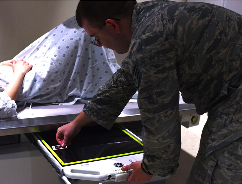 Staff Sgt. Jason Spearow, 341st Medical Support Squadron NCO in charge of diagnostic imaging, administers an x-ray in the control room Feb. 15, 2017, at Malmstrom Air Force Base, Mont. Because the human body is physiologically symmetrical, the technician places a magnet on a slide-out tray on the therapeutic x-ray table to identify which side of the body is in the image. (U.S. Air Force photo/Senior Airman Jaeda Tookes) 