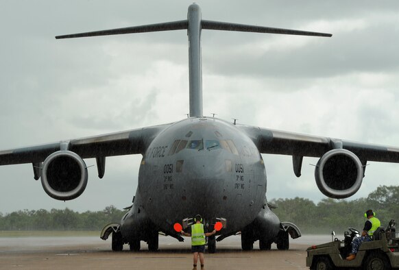 A member of the Royal Australian Air Force marshals a U.S. Air Force C-17 Globemaster, arriving from Joint Base Elmendorf-Richardson, Alaska, on the flightline at Royal Australian Air Force (RAAF) Base Tindal, Feb. 13, 2017. U.S. Airmen arrived via the C-17 to support twelve F-22 Raptors, joining approximately 200 Airmen at RAAF Base Tindal as part of the Enhanced Air Cooperation (EAC) Initiative under the Force Posture Agreement between the U.S. and Australia. EAC creates the foundation for an enhanced rotational presence of U.S. military personnel in Australia to promote interoperability, build upon our already strong alliance, and reaffirm our commitment to the Indo-Asia-Pacific region.  (U.S. Air Force photo/Staff Sgt. Alexander Martinez)