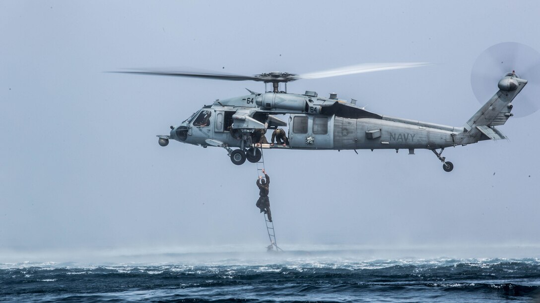 A Marine with the Maritime Raid  Force climbs a caving ladder attached to an MH-60 Seahawk during a helocast training evolution near the USS Makin Island (LHD 8) afloat in the Indian Ocean, Nov. 28, 2016. The training consisted of Marines jumping out of CH-53 Super Stallions with a Combat Rubber Raiding Craft, which simulated the MRF team traveling a long distance before being dropped in the ocean to continue their mission using a CRRC. The Marines are with the 11th Marine Expeditionary Unit. 