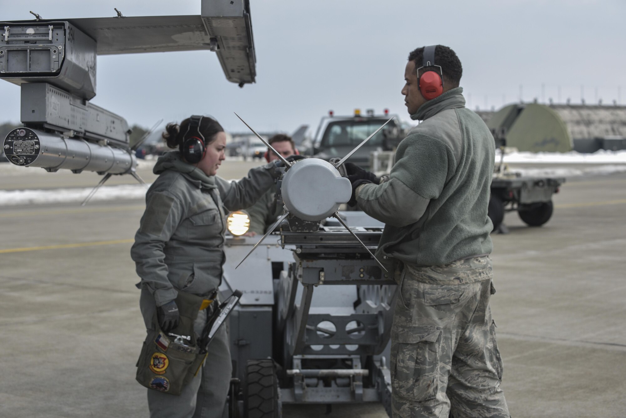 U.S. Air Force Staff Sgt. Zion Monica, left, a weapons load crew chief with the 14th Aircraft Maintenance Unit,  and Senior Airman Anthony Molero, right, a weapons load crewmember with the 14th AMU, guides an AIM-120 advanced medium range air-to-air missile onto an F-16 Fighting Falcon at Misawa Air Base, Japan, Feb. 16, 2017. The 13th Fighter Squadron flies 36 sorties a day during a three-day surge. Airmen work around the clock to increase mission capabilities supporting contingencies anytime and anywhere. (U.S. Air Force photo by Staff Sgt. Melanie Hutto)