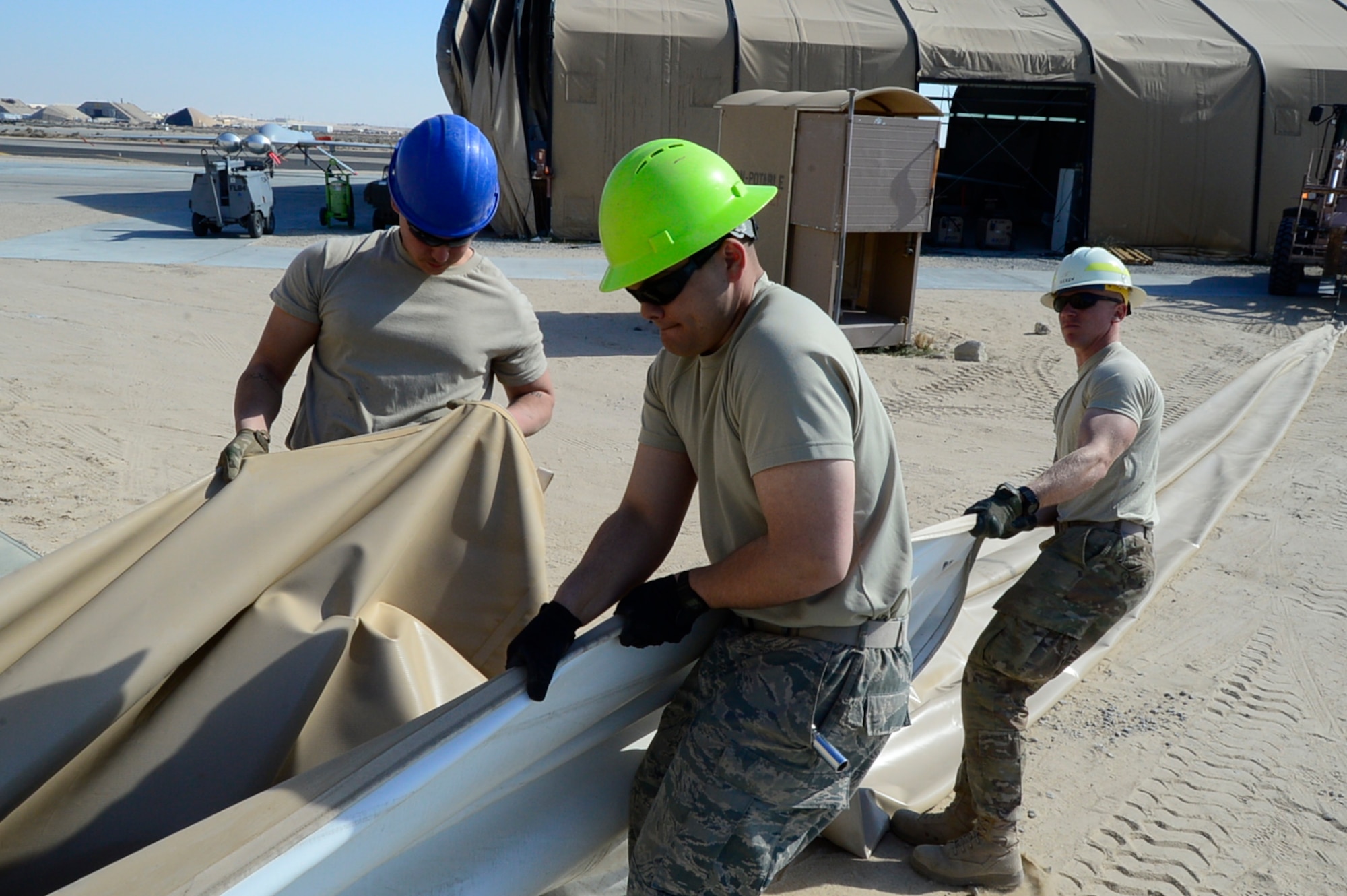 U.S. Air Force Airman 1st Class Nicholas Lockhart, 386th Expeditionary Civil Engineer Squadron pavements and equipment journeyman, left, Senior Airman Jacob Sullivan, 386th ECES water and fuels management journeyman, center, and Staff Sgt. Alex Geren, 557th Expeditionary Prime BEEF Squadron electrician, right, pull canvas off a large aircraft maintenance shelter at an undisclosed location in Southwest Asia, Feb. 8, 2017. The LAMS was being torn down in order to make room for the 386th Air Expeditionary Wing to house a fleet of MQ-9 Reapers. (U.S. Air Force photo by Capt. Casey Osborne)