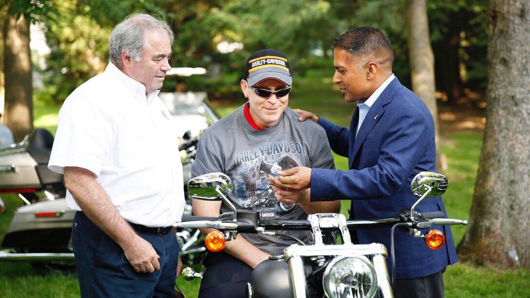 John Bryant, a quality assurance specialist with Defense Contract Management Agency International in Ottawa, Canada, is presented the keys to a Harley Davidson Breakout by Lynn Norton, left, dealer principal for Freedom Harley Davidson, Ottawa and Anoop Prakas, managing director for Harley Davidson Canada, July 4, 2016. The motorcycle was a gift from his wife after a successful battle against cancer. (Photo courtesy of Patrick Norton)