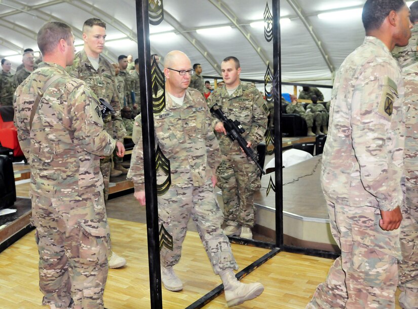 A Soldier takes the ceremonial step across the Non-Commissioned Officer archway during the 863rd Engineer Battalion’s NCO Induction Ceremony at Camp Buerhing, Kuwait, Dec. 8, 2016.  Approximately 100 Soldiers participated in the ceremony signifying the transition from enlisted to the rank of Sergeant.  (Photo by U.S. Army National Guard Capt. Maria Mengrone/Released)