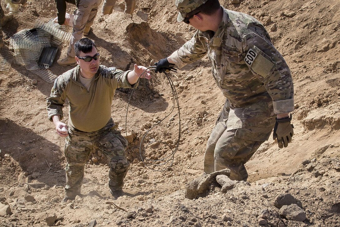 Air Force Staff Sgt. Zachary Flessner, right, hands a detonation cord to Air Force Tech. Sgt. Christopher Wnuk during a range detonation in Southwest Asia, Feb. 11, 2017. Flessner and Wnuk are explosive ordnance disposal technicians assigned to the 332nd Expeditionary Civil Engineer Squadron. Air Force photo by Staff Sgt. Eboni Reams