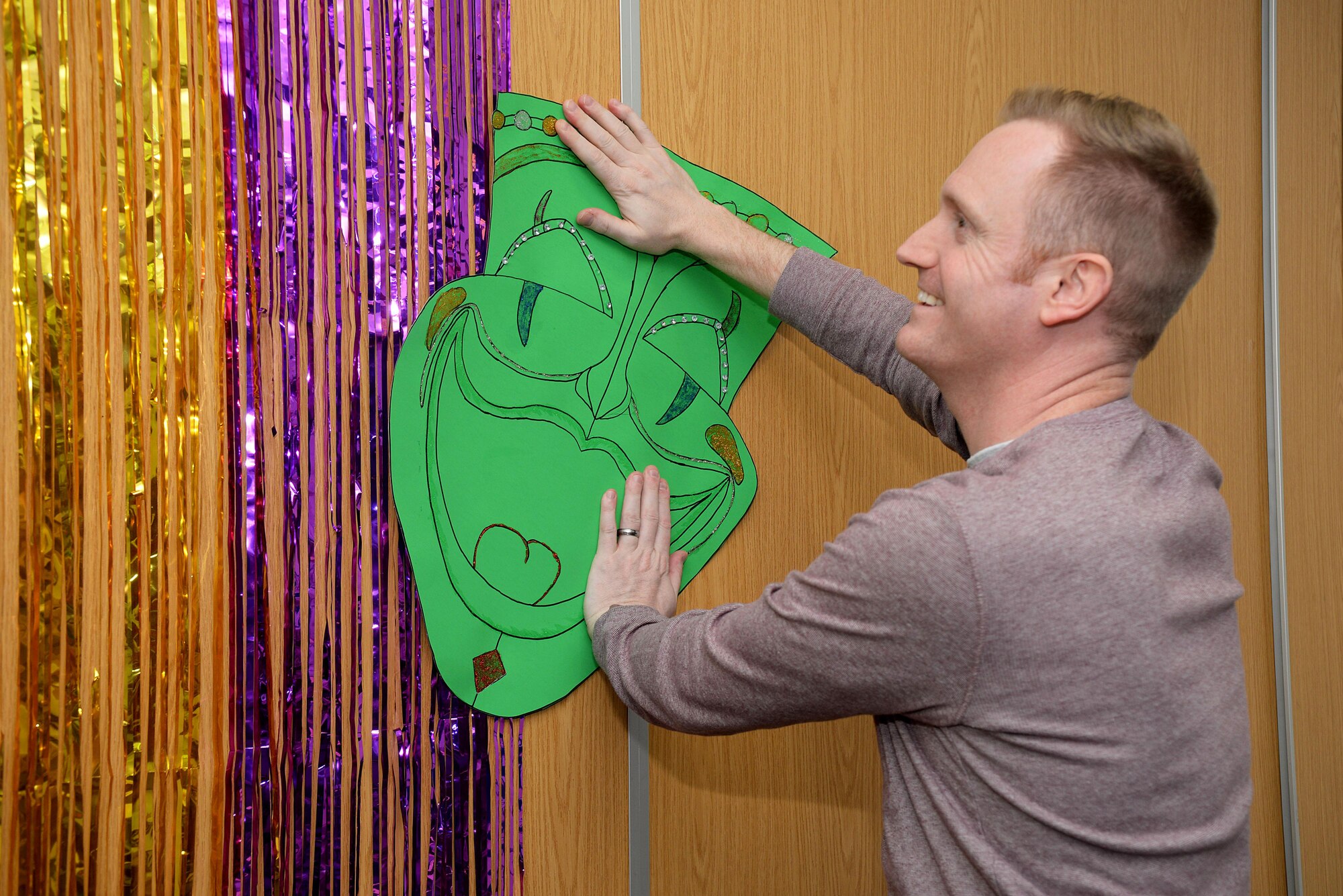 U.S. Air Force Master Sgt. Lucas Shay, 100th Air Refueling Wing first sergeant and superintendent of safety, arranges the backdrop for the photo booth for the Hearts Apart event Feb. 16, 2017, on RAF Mildenhall, England. The 100th Wing Staff Agency and 100th Comptroller Squadron hosted this month’s Hearts Apart event.  (U.S. Air Force photo by Airman 1st Class Tenley Long)