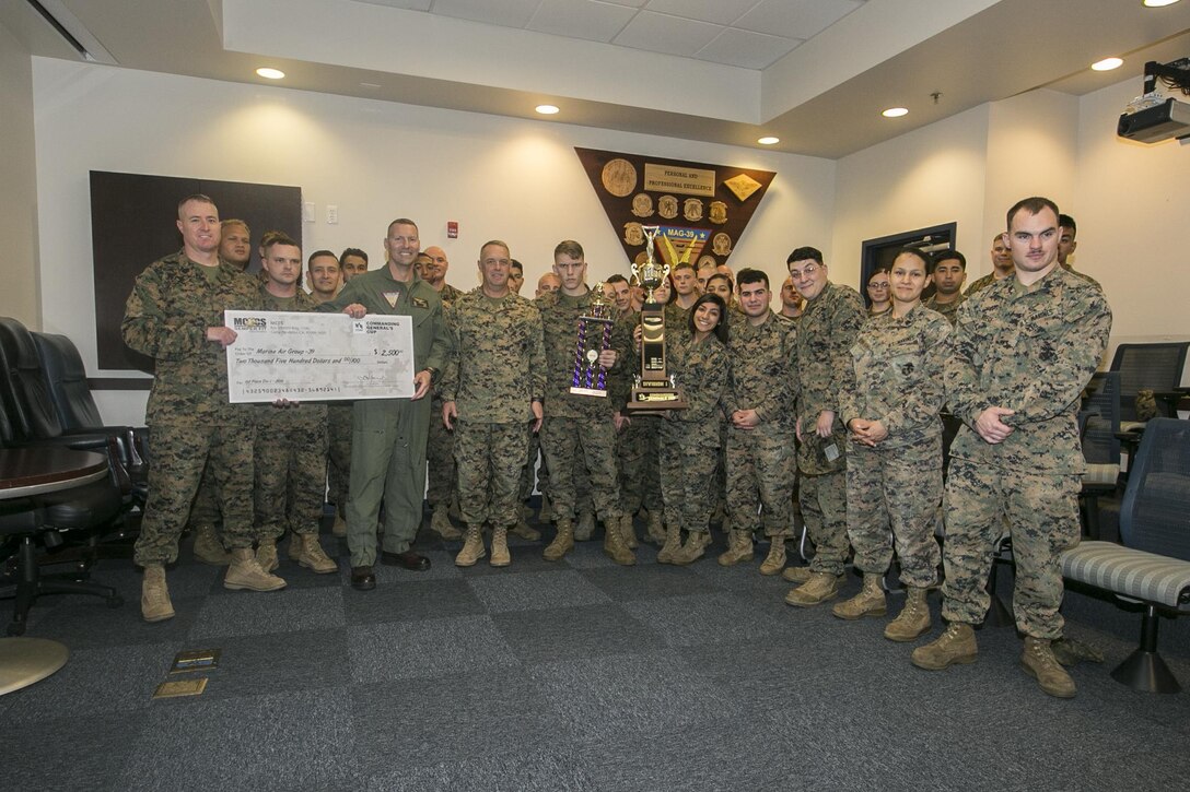 Marines with Marine Aircraft Group (MAG) 39 pose for a photo with the check and trophies awarded for winning the Marine Corps Installations West Commanding General's Cup at Marine Corps Base Camp Pendleton, Calif., Feb. 7. The CG Cup is a competition which allows Marine Corps units at the West Coast bases to come together for a friendly competition. (US Marine Corps photo by Cpl. Brian Bekkala/Released)