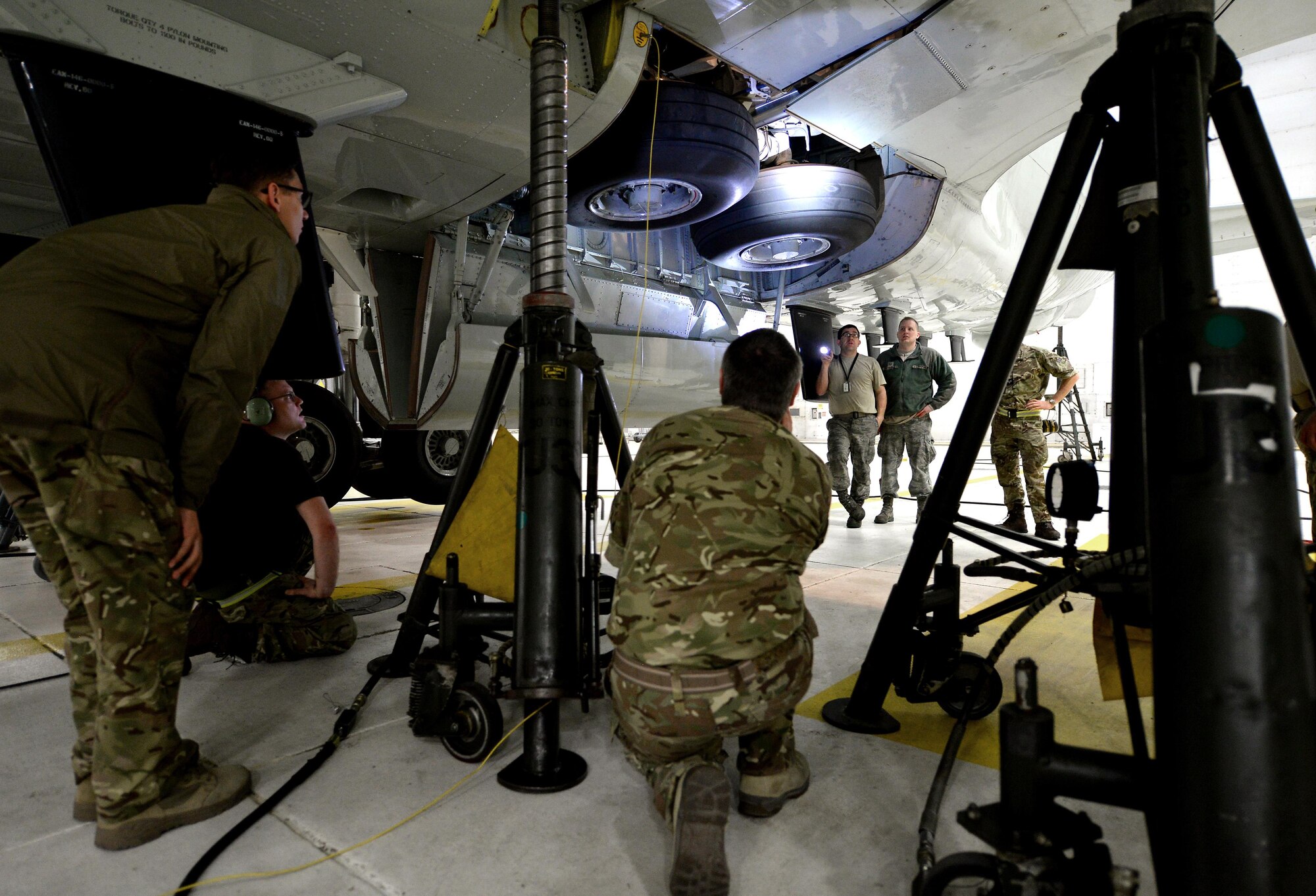 Royal Air Force 51 Squadron and 55th Maintenance Squadron maintenance personnel troubleshoot landing gear problems on a RAF RC-135 Airseeker suspended by 30 ton aircraft jacks inside a hangar at Offutt Air Force Base, Neb. Feb. 12. The aircraft diverted from Nellis Air Force Base to Offutt where it received maintenance assistance from the 55th MXG to correct a landing gear problem that occurred while participating in a joint exercise. (U.S. Air Force photo by Delanie Stafford)