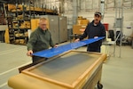 David Bachelder and Jimmy Abney with the Heavy Repair Carpenter Shop lay plexiglass on a custom-made frame.  (U.S. Air Force photo / Gene Barnett)