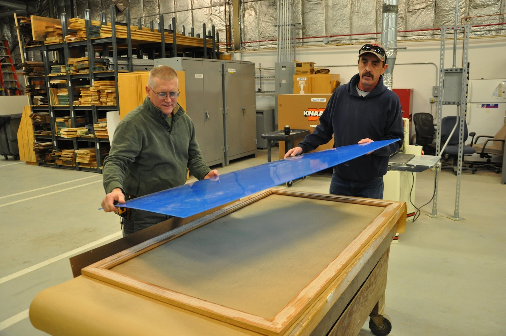 David Bachelder and Jimmy Abney with the Heavy Repair Carpenter Shop lay plexiglass on a custom-made frame.  (U.S. Air Force photo / Gene Barnett)