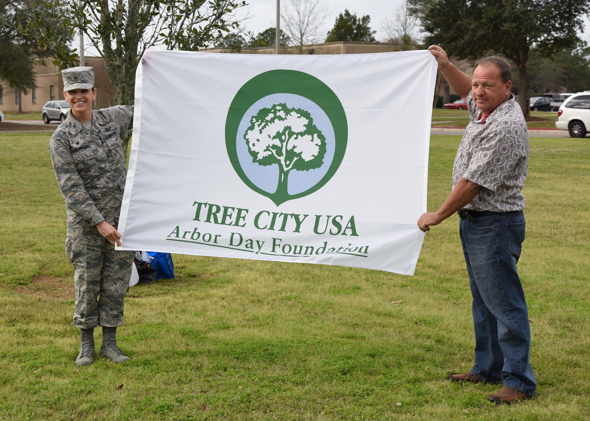 Col. Michele Edmondson, 81st Training Wing commander, and Eric Nolan, Biloxi Arborist and Mississippi Forestry Commission executive board member, display a Tree City USA flag during an Arbor Day celebration outside the child development center Feb. 14, 2017, on Keesler Air Force Base, Miss. Keesler AFB earned the national Tree City USA honor from the Arbor Day Foundation for its 24th consecutive year. (U.S. Air Force photo by Kemberly Groue)
