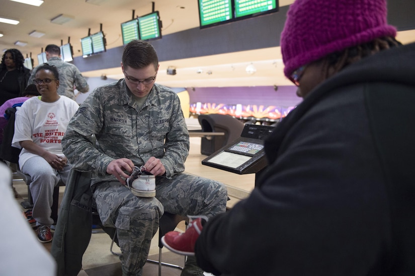 Senior Airman Mitchell Henriksen, 11th Logistics Readiness Squadron logistics planner, helps a District of Columbia Special Olympics athlete untie her bowling shoes before the 2017 D.C. Special Olympics Bowling Championship at Hyattsville, Md., Feb. 16, 2017. Volunteers were encouraged to help with equipment, keep score, get to know the athletes and cheer them on throughout the tournament. (U.S. Air Force photo by Senior Airman Philip Bryant)
