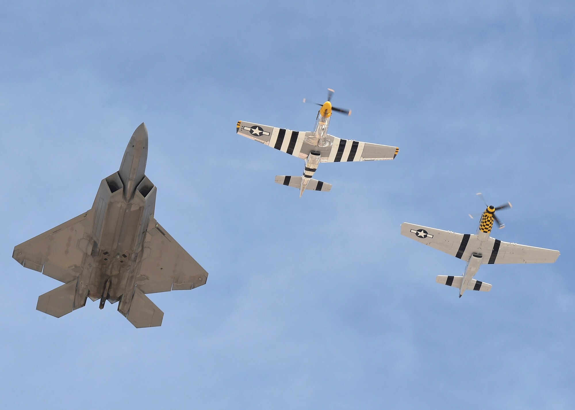 An F-22 Raptor and two P-51 Mustangs fly in formation during the Heritage Flight Training and Certification Course Feb. 9, 2017, at Davis-Monthan Air Force Base, Ariz. Heritage and demonstration teams need to be certified annually to participate in open houses and air shows worldwide. (U.S. Air Force photo by Senior Airman James Hensley)