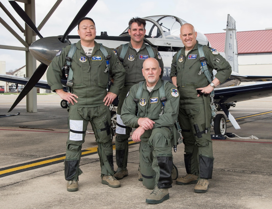 Col. Don Kang (L) SAF-MR senior policy advisor, Maj. Andy Van De Walle (C) and Lt. Col. Andrew Kissinger (R), both with the 39 FTS, pause for a photo before taking John Fedrico (kneeling), deputy assistant Secretary of the Air Force for  Reserve Affairs and Airman Readiness on a T-6 orientation flight during his visit to Joint Base San Antonio-Randolph, Texas on Feb. 13. Fedrico’s visit, hosted by the 340 FTG, served a dual purpose. Fedrico presented a letter of thanks to one of the unit’s own, retired Air Force Lt. Col. Todd Ernst, for his efforts to help ensure families of Reserve and Guard service members receive the same survivor benefits as active duty service members. Fedrico also received a mission brief and got to experience the unit’s operations first hand. (Air Force photo by Sean Worrell, Joint Base San Antonio-Randolph Public Affairs)