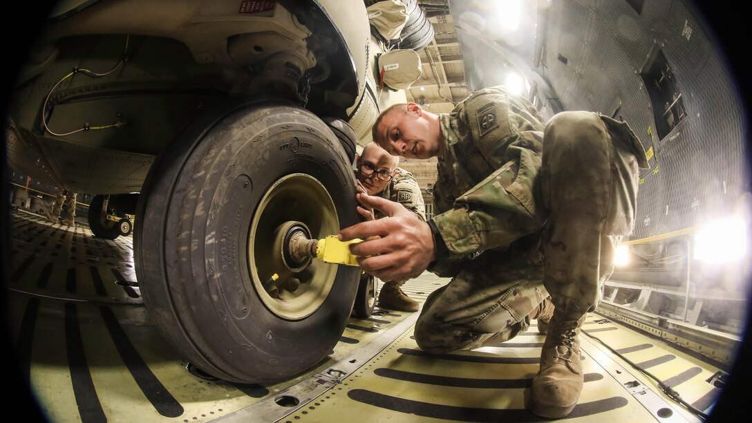 A soldier unlocks a CH-47F Chinook wheel before offloading the helicopter from a C-5M Super Galaxy at Pope Field, N.C., Feb. 14, 2017. The soldier is assigned to the 82nd Combat Aviation Brigade. Army photo by Capt. Adan Cazarez